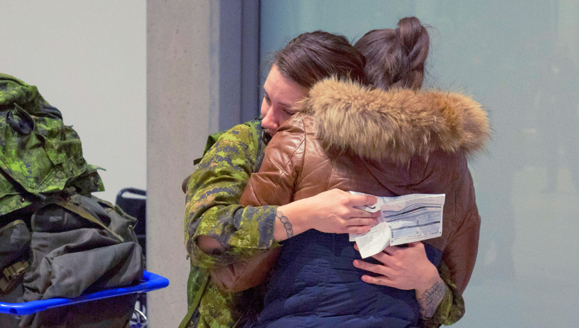 Deploying military member hugging a woman