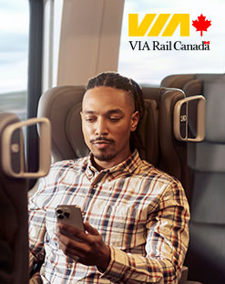 man on train looking at phone, VIA logo