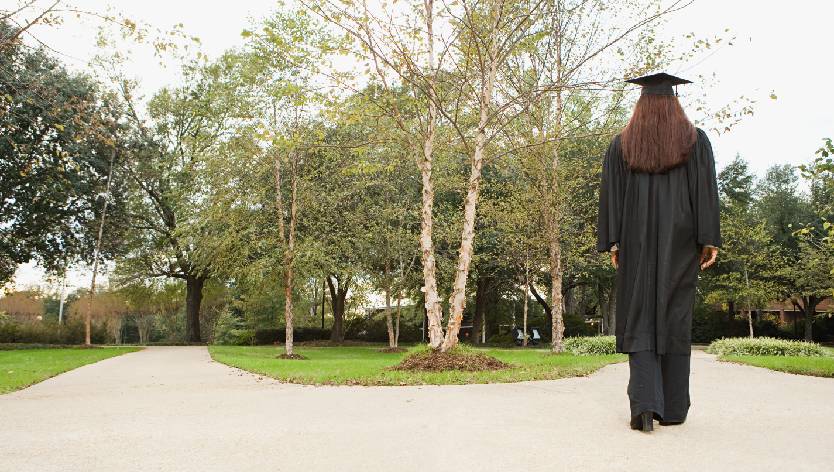Female graduate walking down a path
