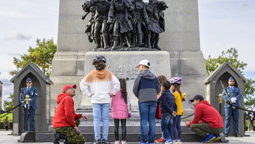 Children and military member at the bottom of memorial statue