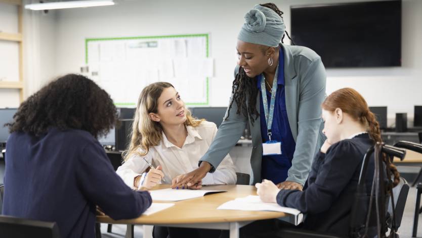 teacher helping high school students in class