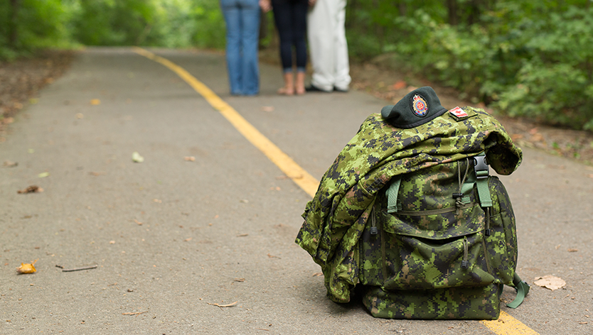 military kit on road with family in background