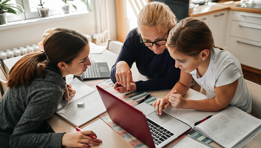 Lady helping two kids with homework