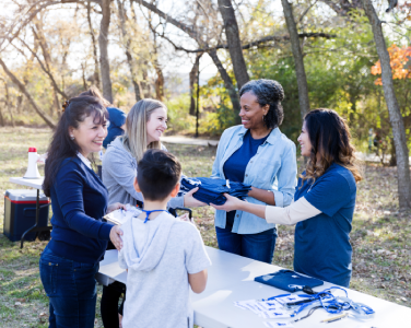 people at a table handing out a shirt