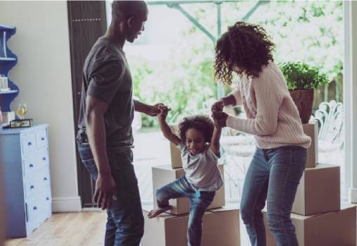 couple playing with small child with moving boxes behind them