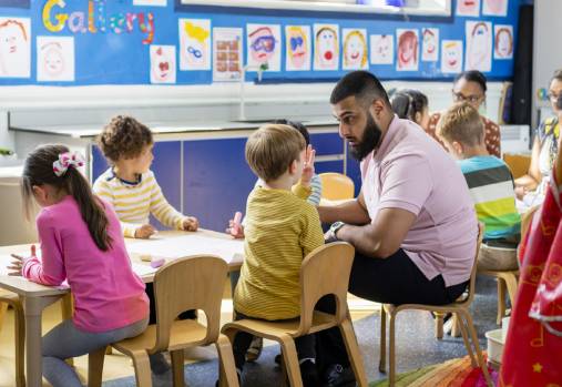 Teacher and children smiling and sitting around a table