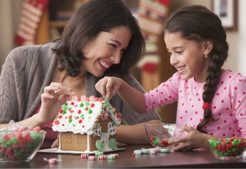 Mother and daughter decorating gingerbread house