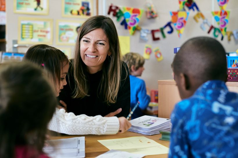 Teacher and children smiling and sitting around a table