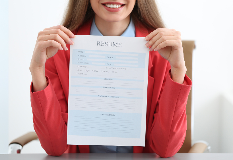 woman smiling and holding resume up 