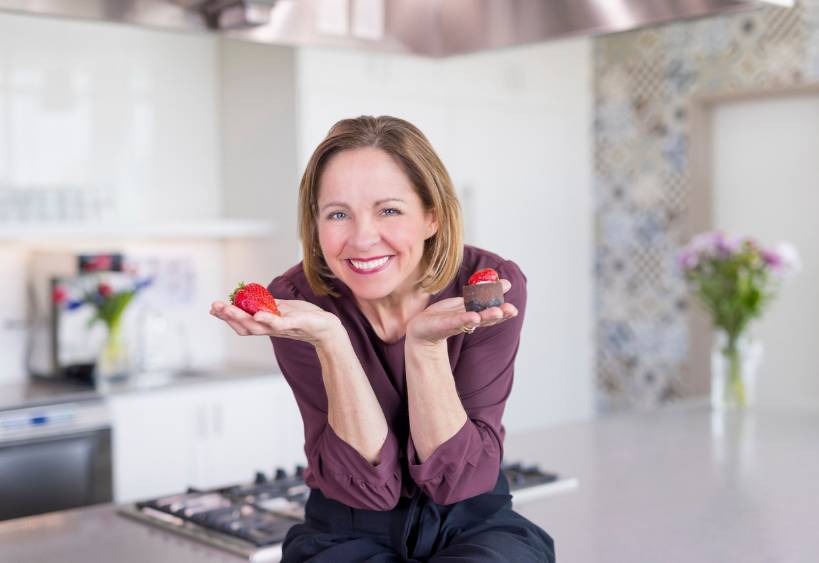 Andrea Holwegner, RD, holding a chocolate in one hand and a strawberry in the other