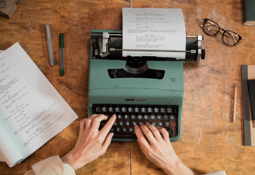 aerial view of hands typing on a green typewriter