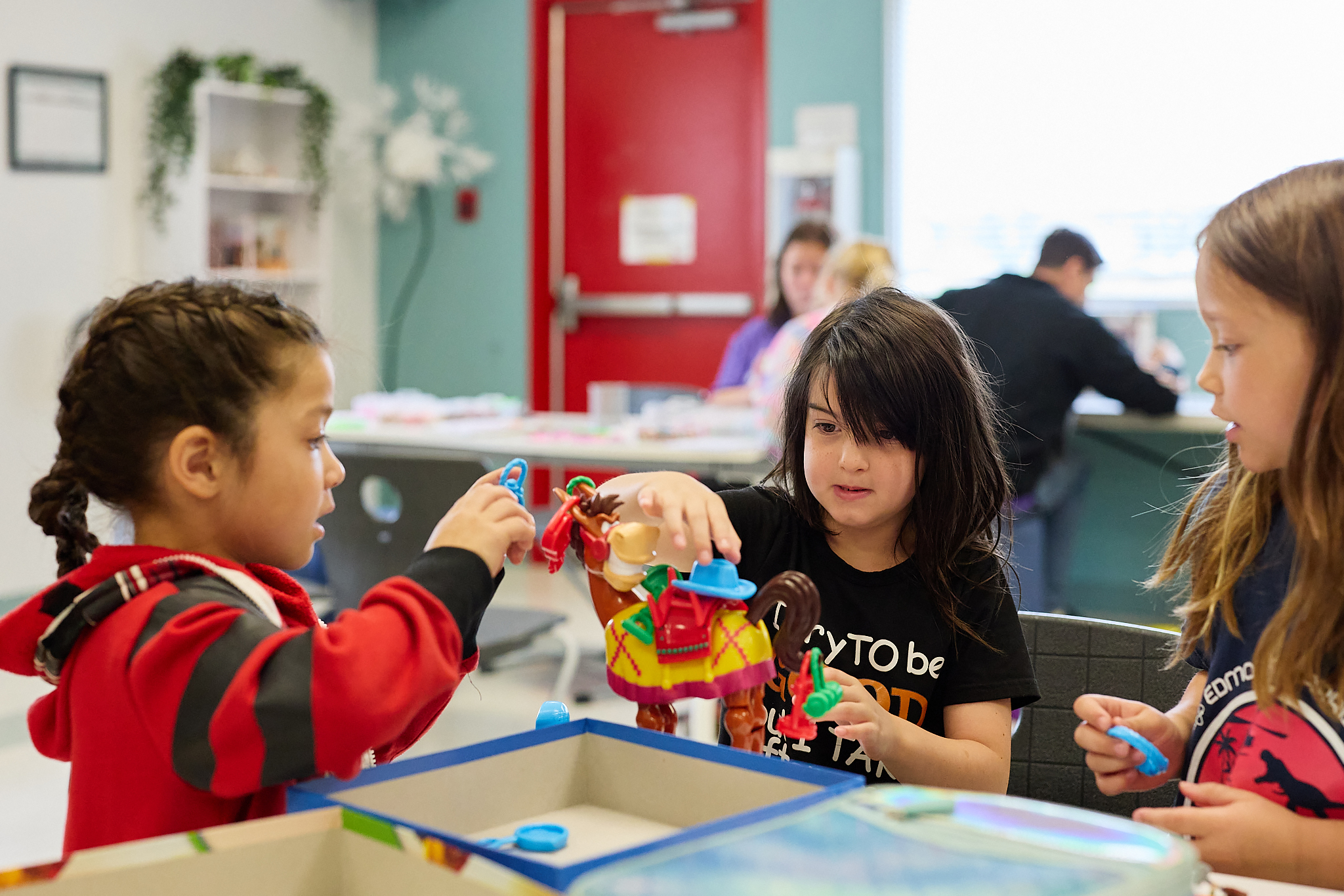 3 school aged children sitting around a table playing a game