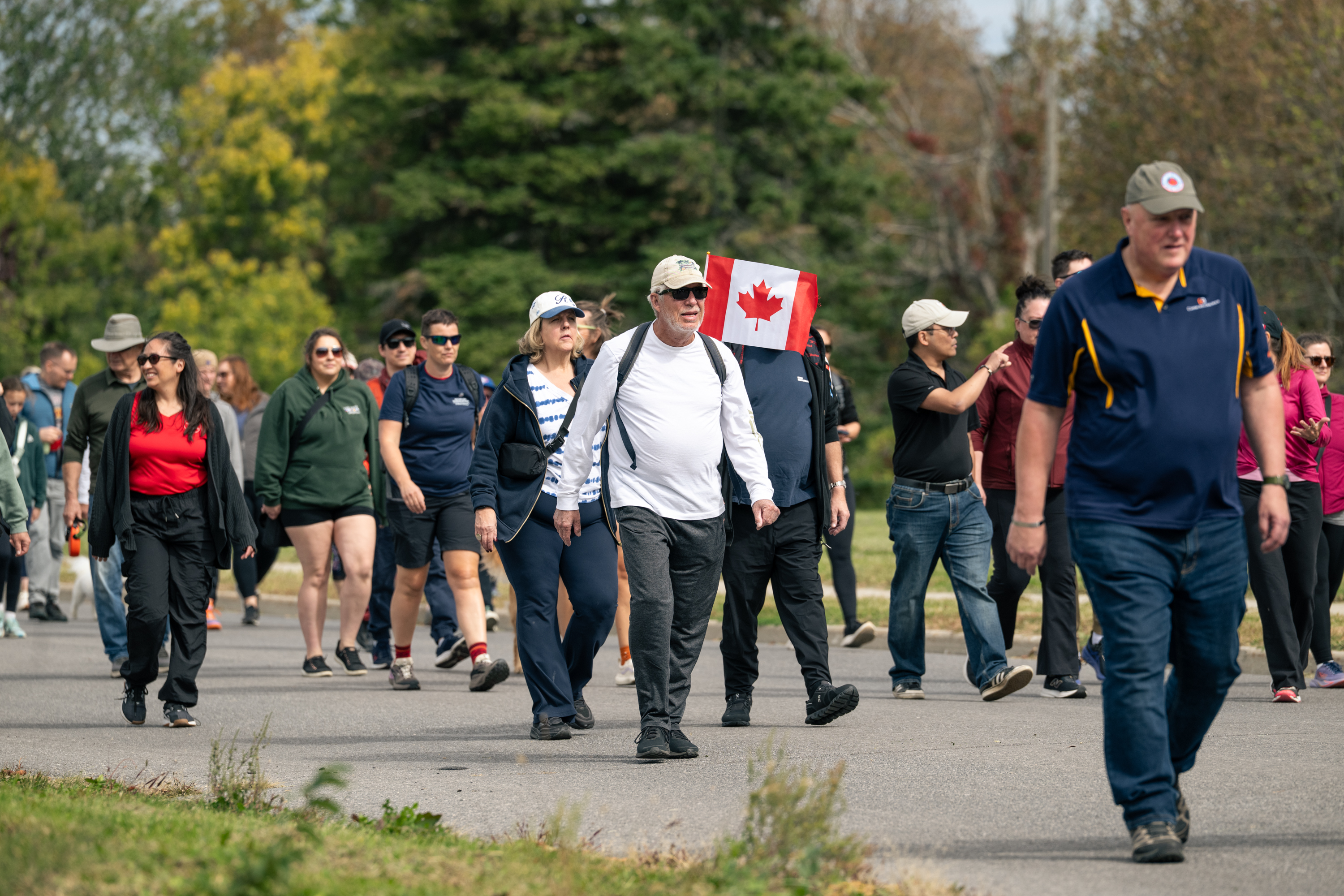 Participants at the Canadian Walk for Veterans carry a banner reading “True Patriot Love” as veterans, military personnel, and community members gather behind them with flags.