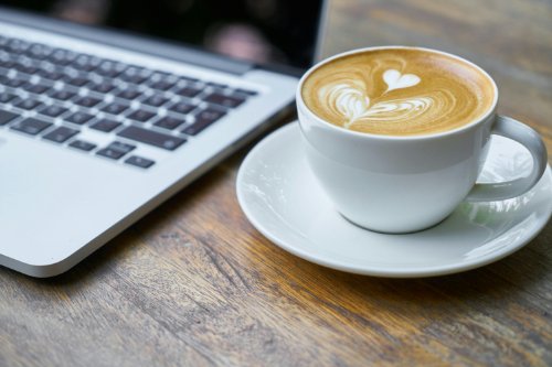latte on wooden table next to laptop